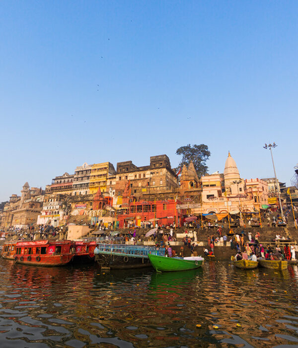Pilgrims bathing in the Ganges at sunrise with boats and historic ghats in Varanasi, India